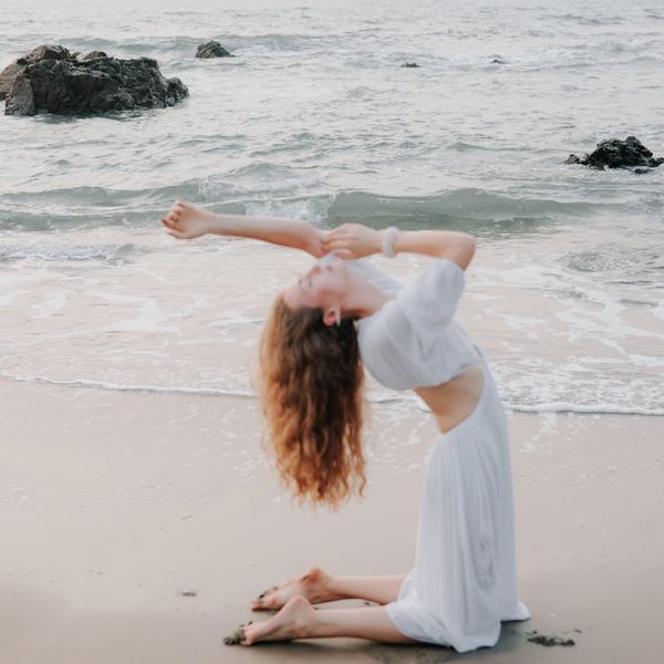 Woman in a graceful yoga pose with an azure ocean color scheme.
